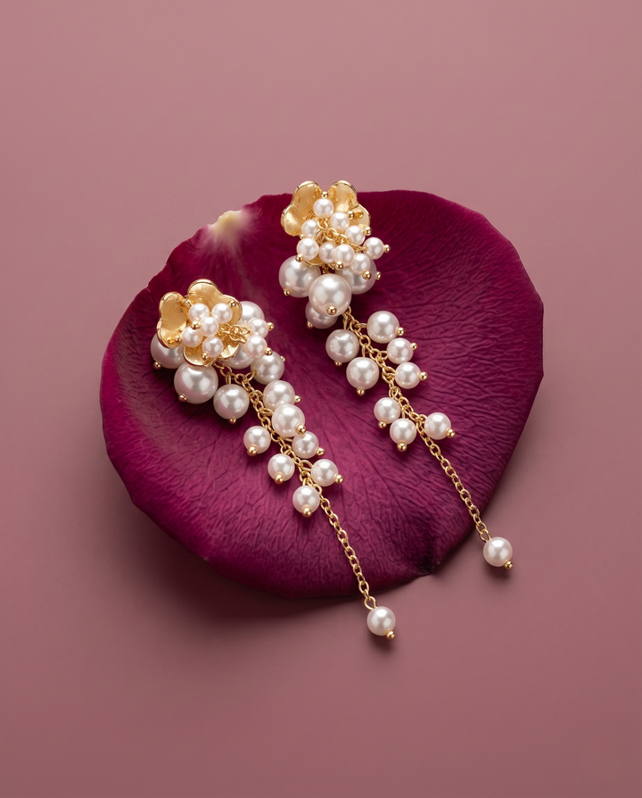 Pearl earrings with gold accents on a purple petal against a matching background
