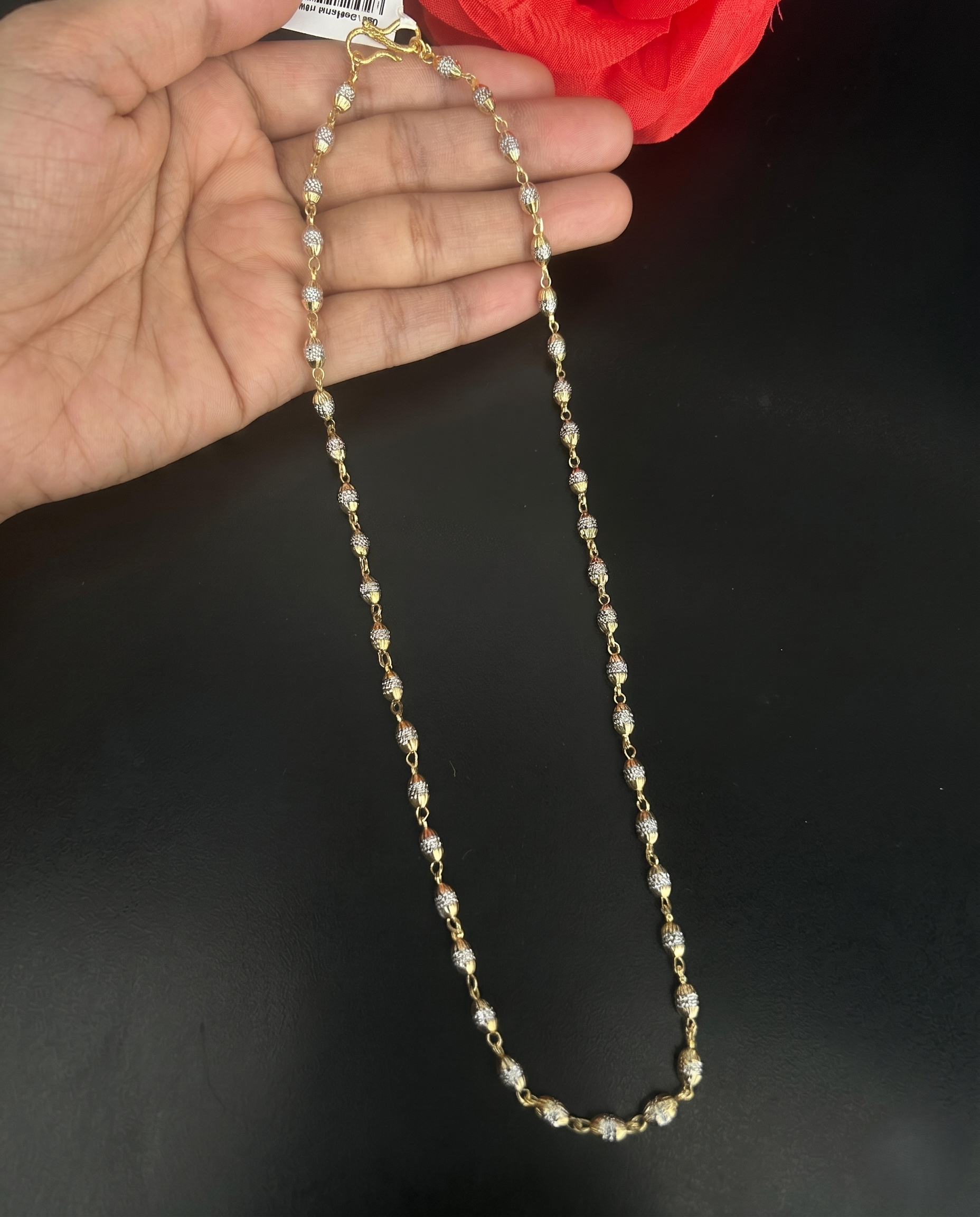 Pearl necklace held by a hand against a dark background