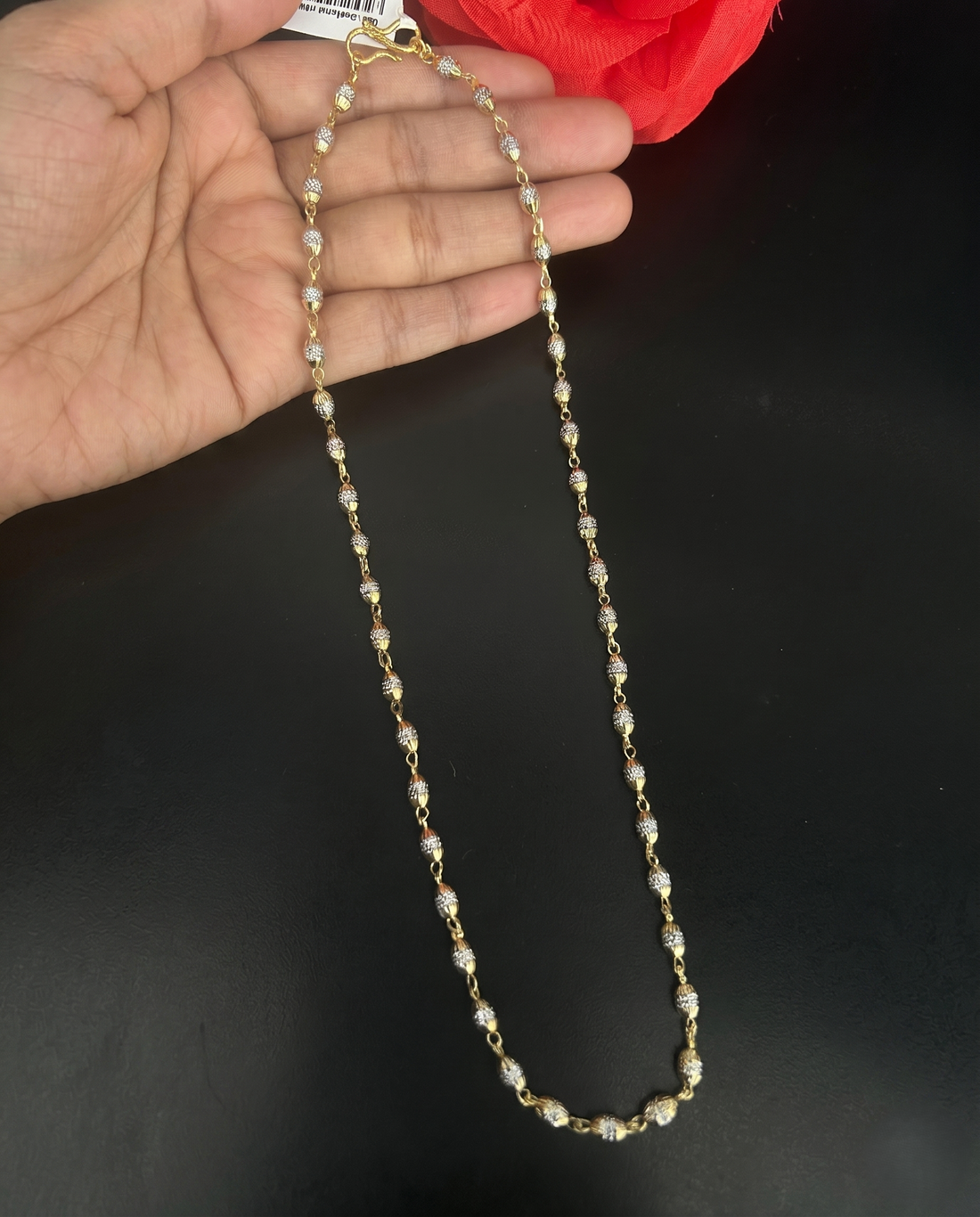Pearl necklace held by a hand against a dark background