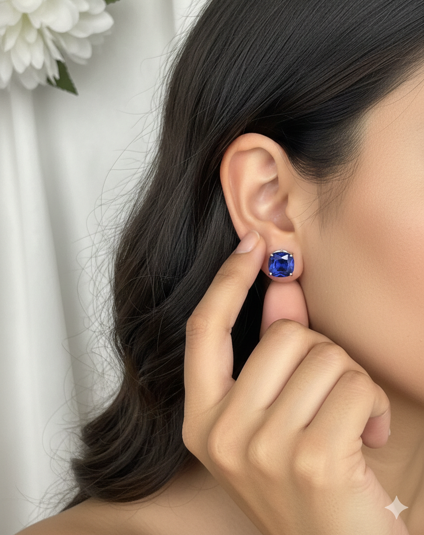 Person wearing a blue gemstone earring with a white flower in the background