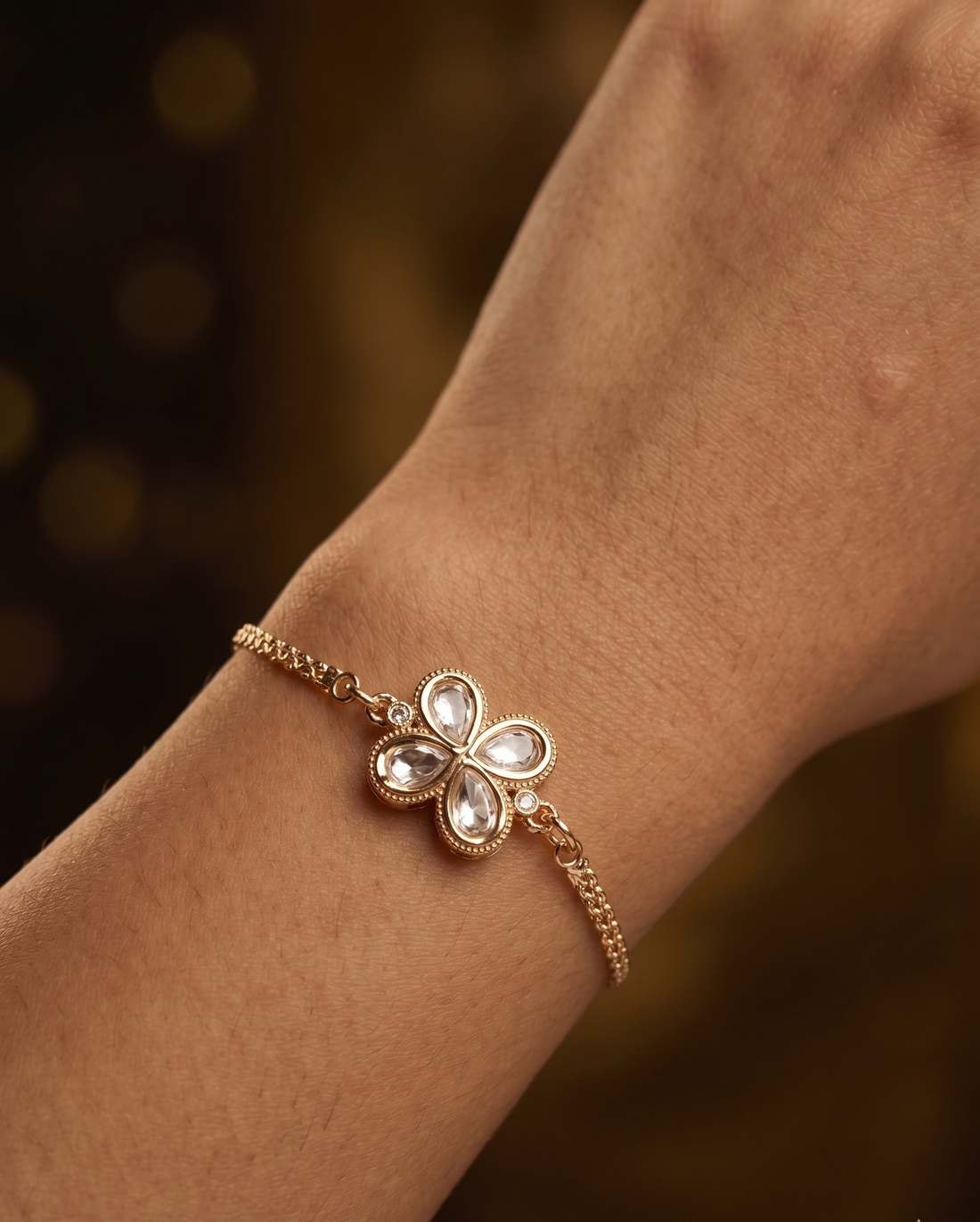 Rose gold bracelet with a floral clasp on a wrist against a blurred background