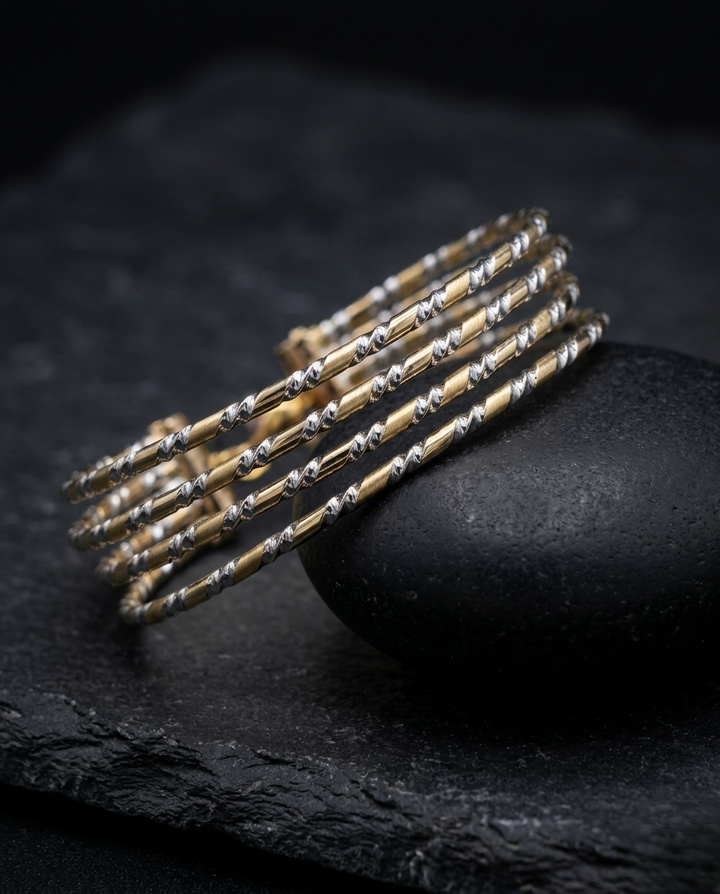 Set of gold and silver bracelets on a dark stone surface
