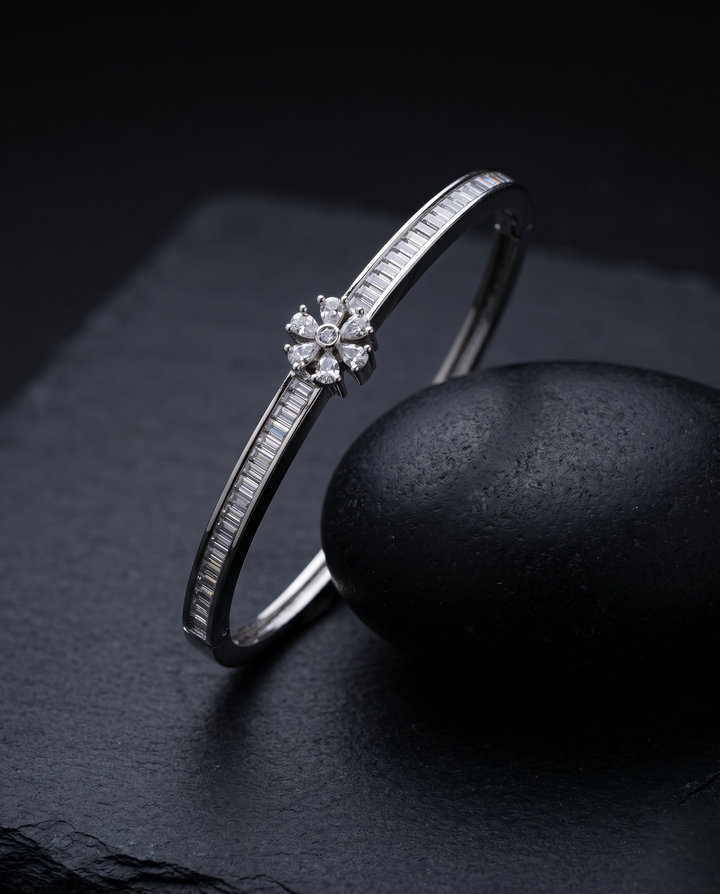 Silver bracelet with a floral diamond clasp on a dark stone surface