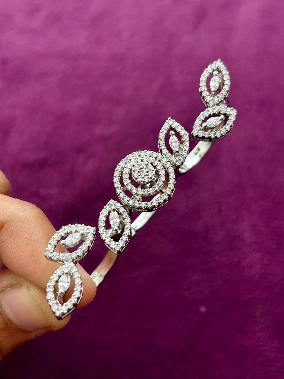 Silver bracelet with diamond-like stones held against a purple background