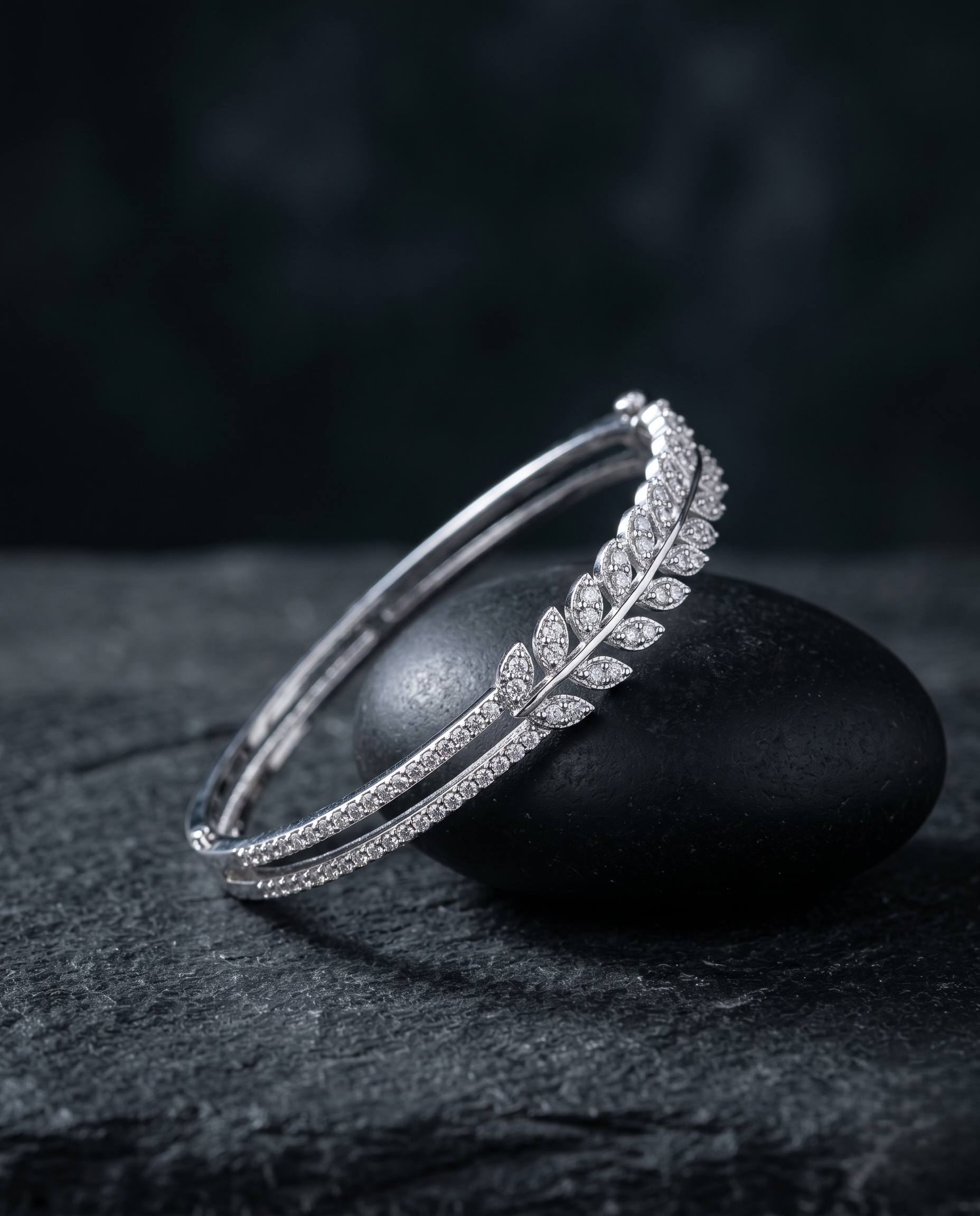 Silver bracelet with leaf design on a dark stone surface