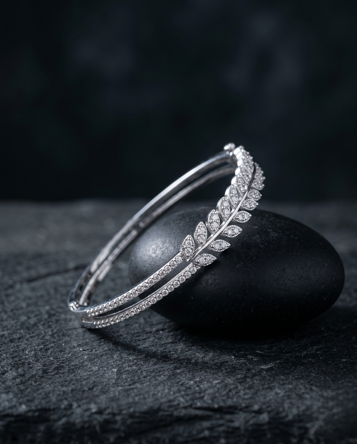 Silver bracelet with leaf design on a dark stone surface
