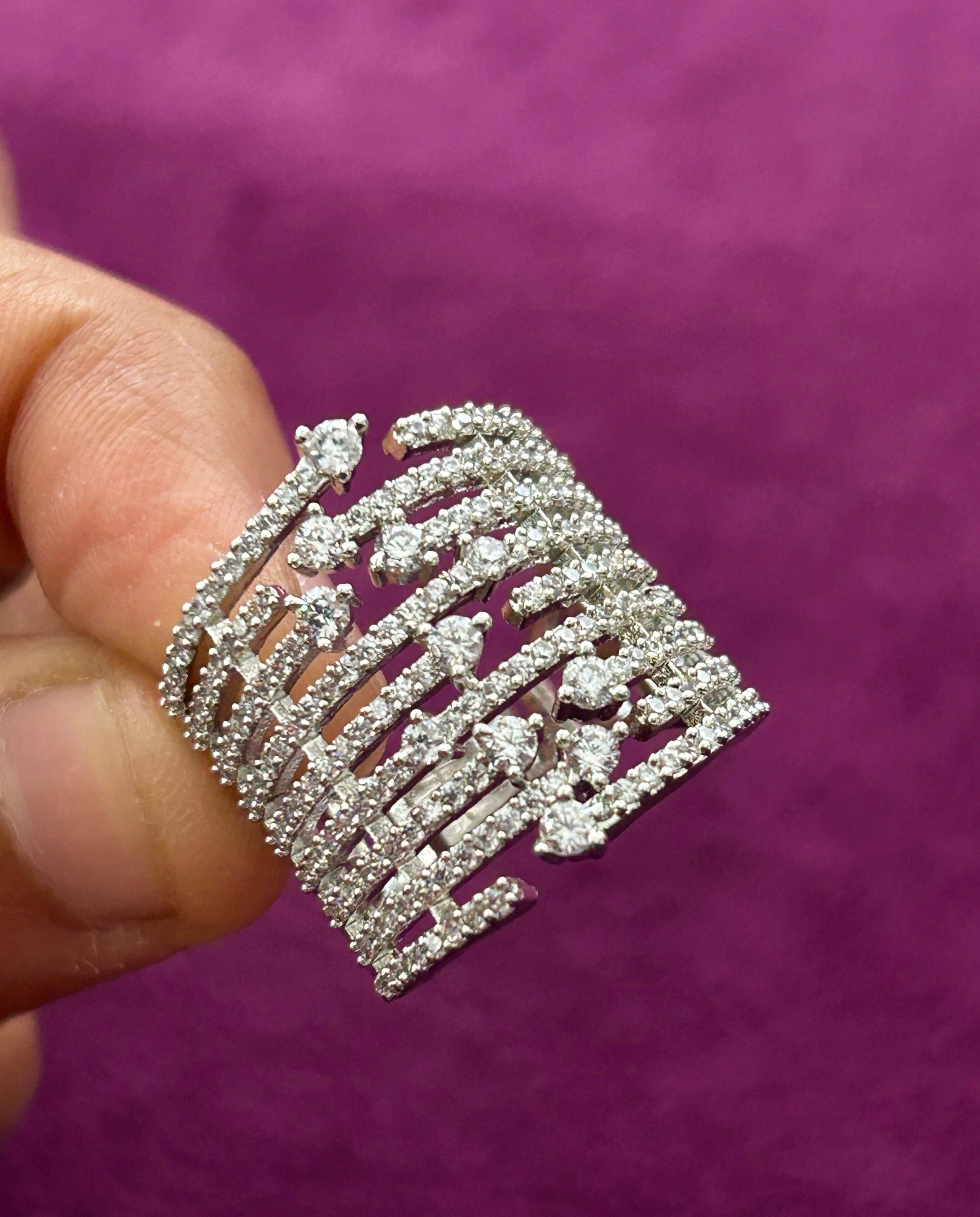 Silver decorative piece held by a hand against a purple background