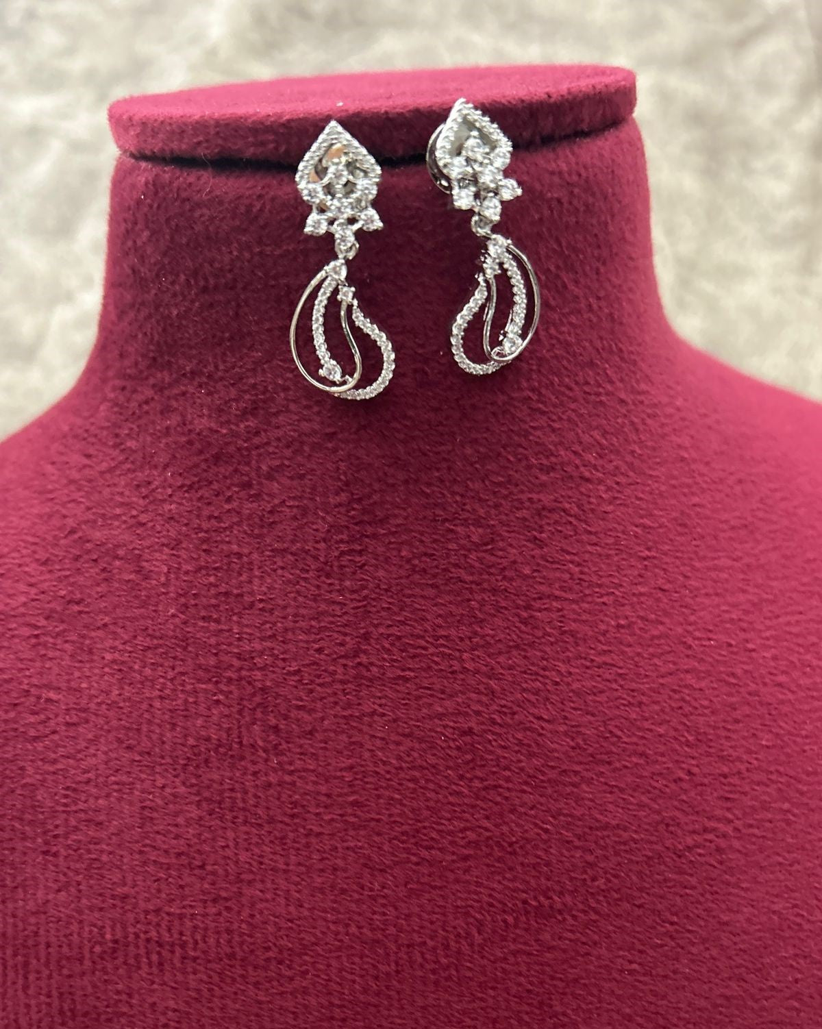 Silver earrings on a red velvet stand with a neutral background
