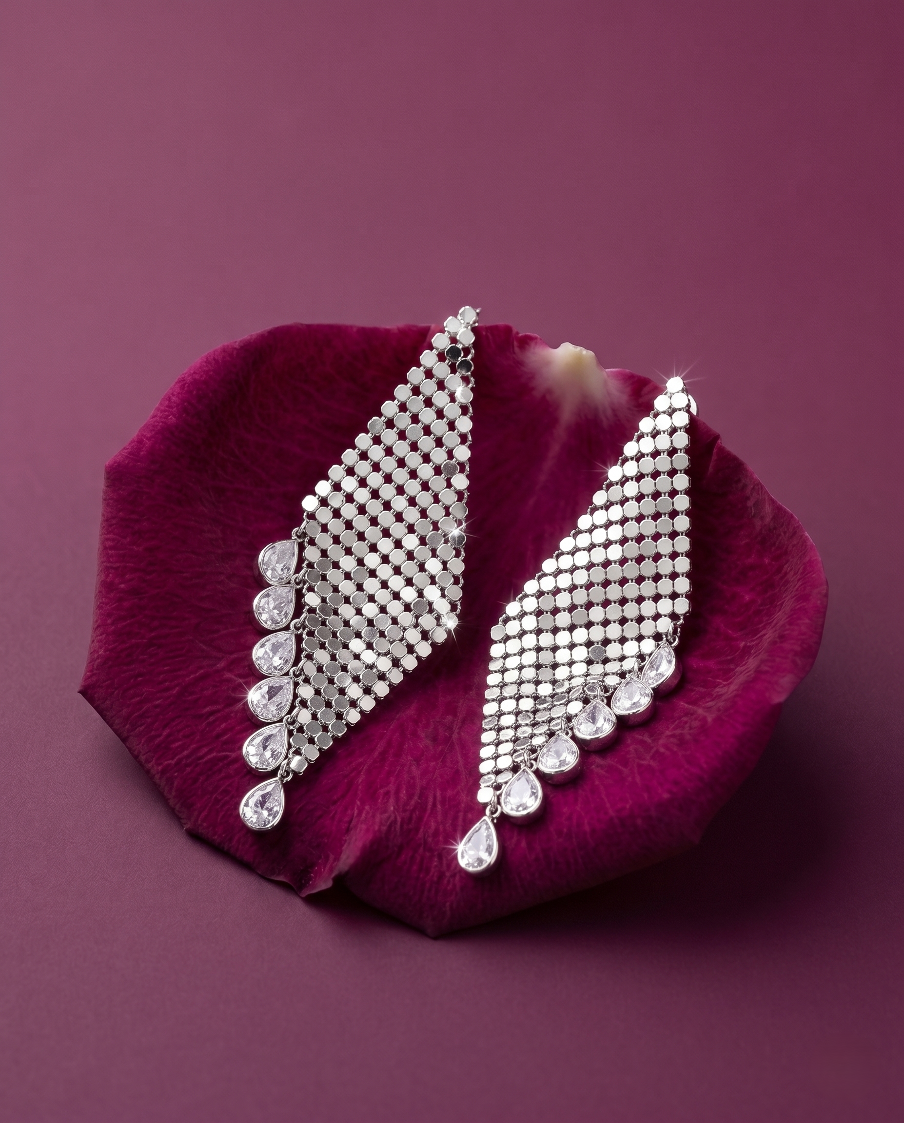 Silver earrings on a purple petal with a purple background