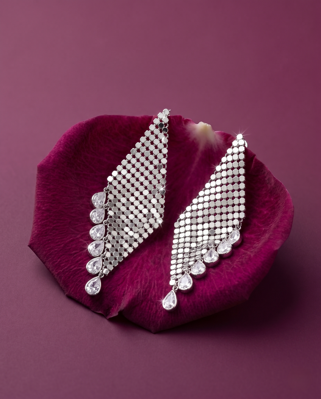 Silver earrings on a purple petal with a purple background