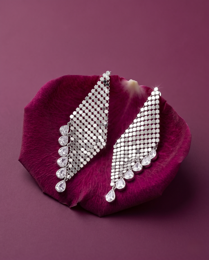 Silver earrings on a purple petal with a purple background