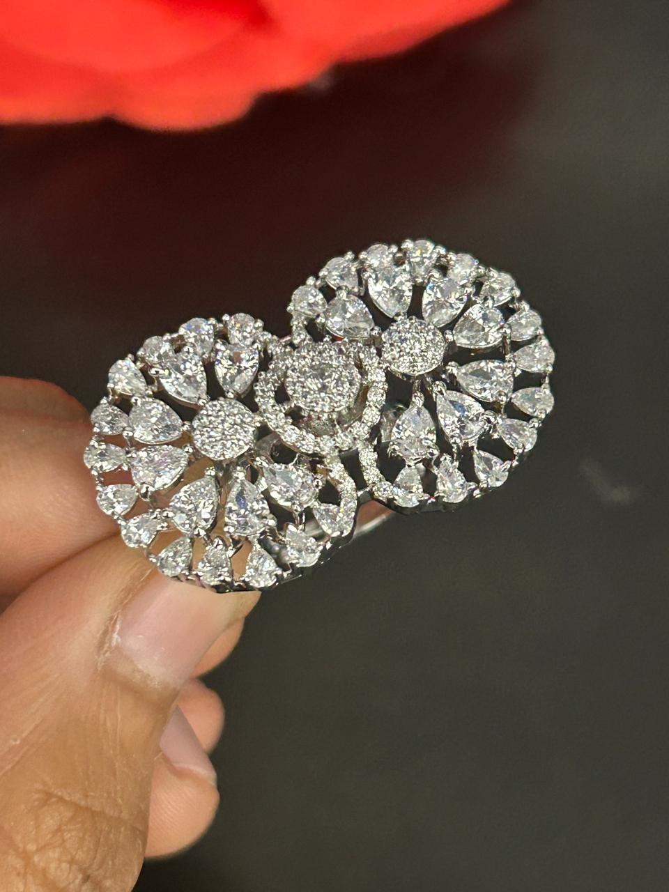 Silver floral brooch held by a hand against a dark background