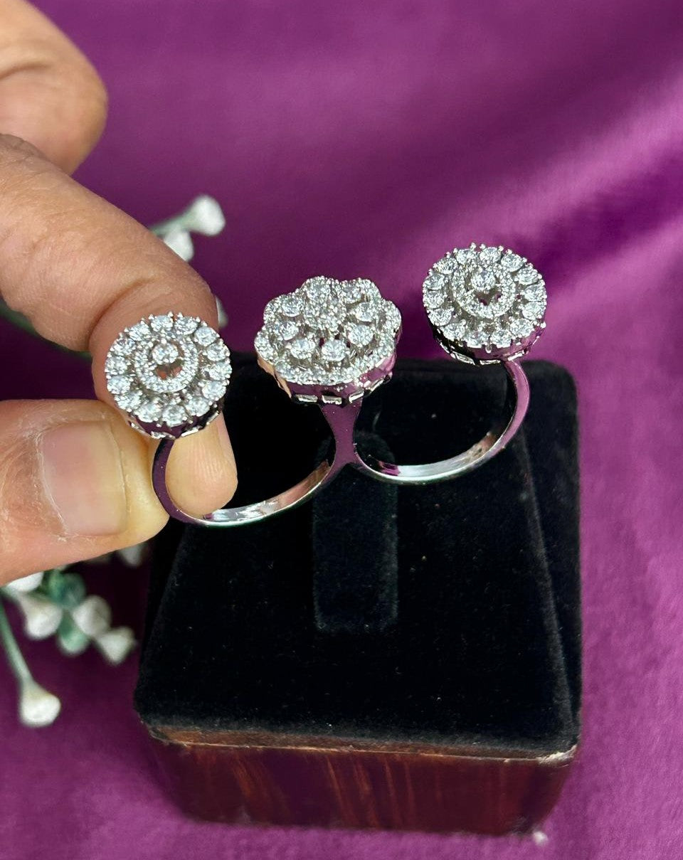 Silver floral earrings with clear stones held by a hand on a purple background
