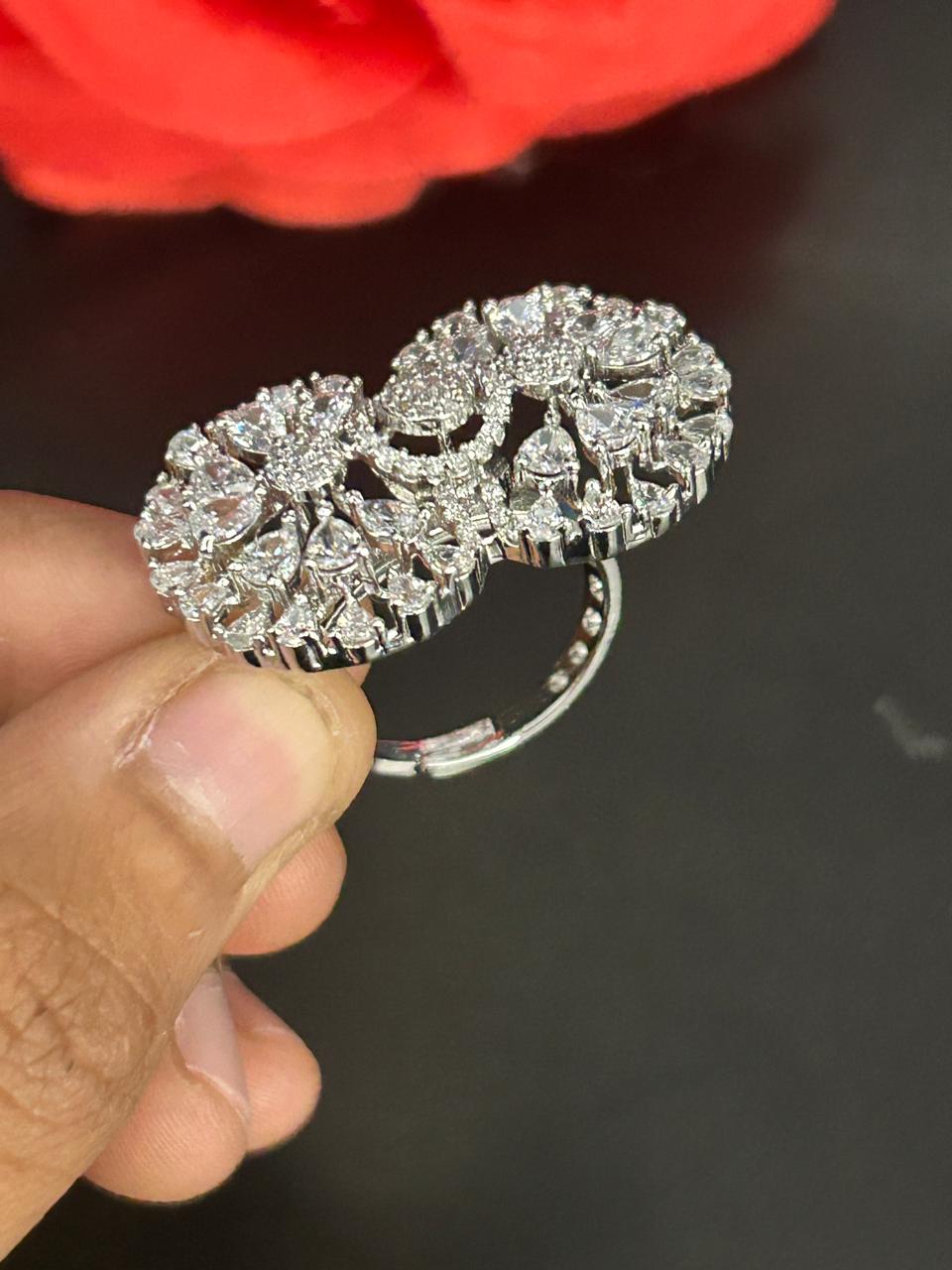 Silver hoop earring with intricate design held by a hand against a dark background