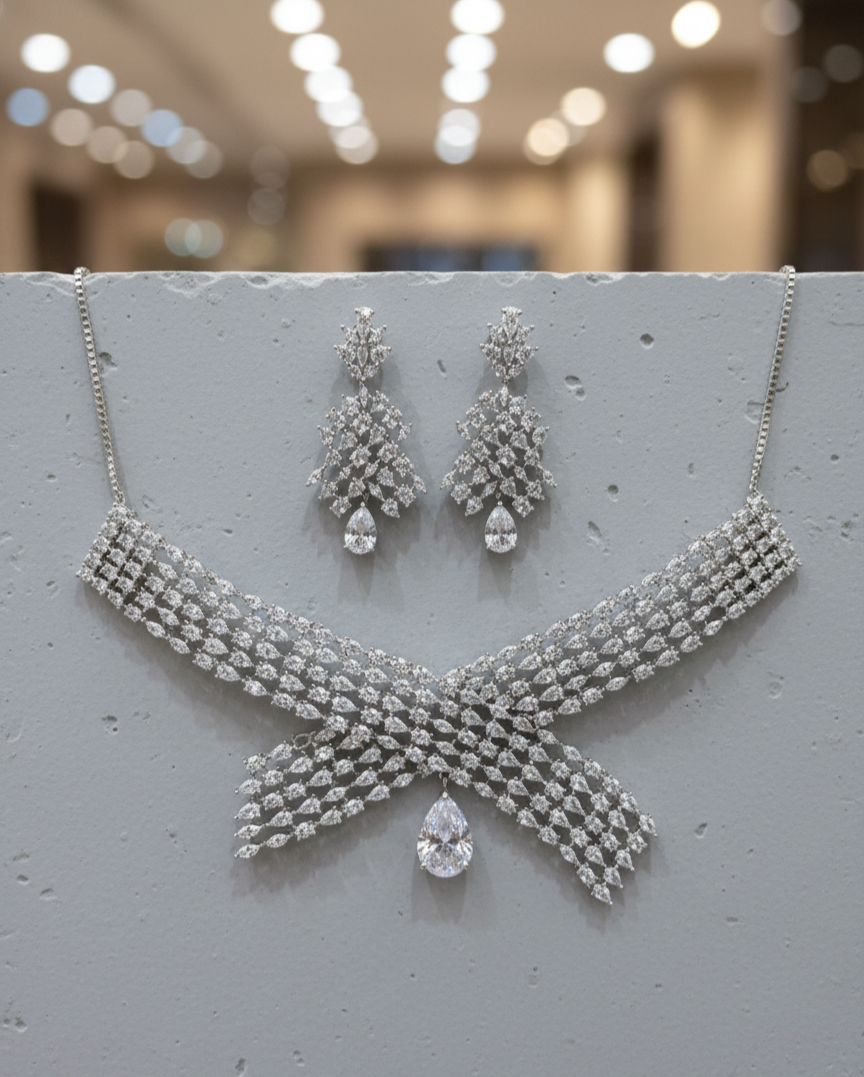 Silver necklace and earrings set on a gray surface with blurred background