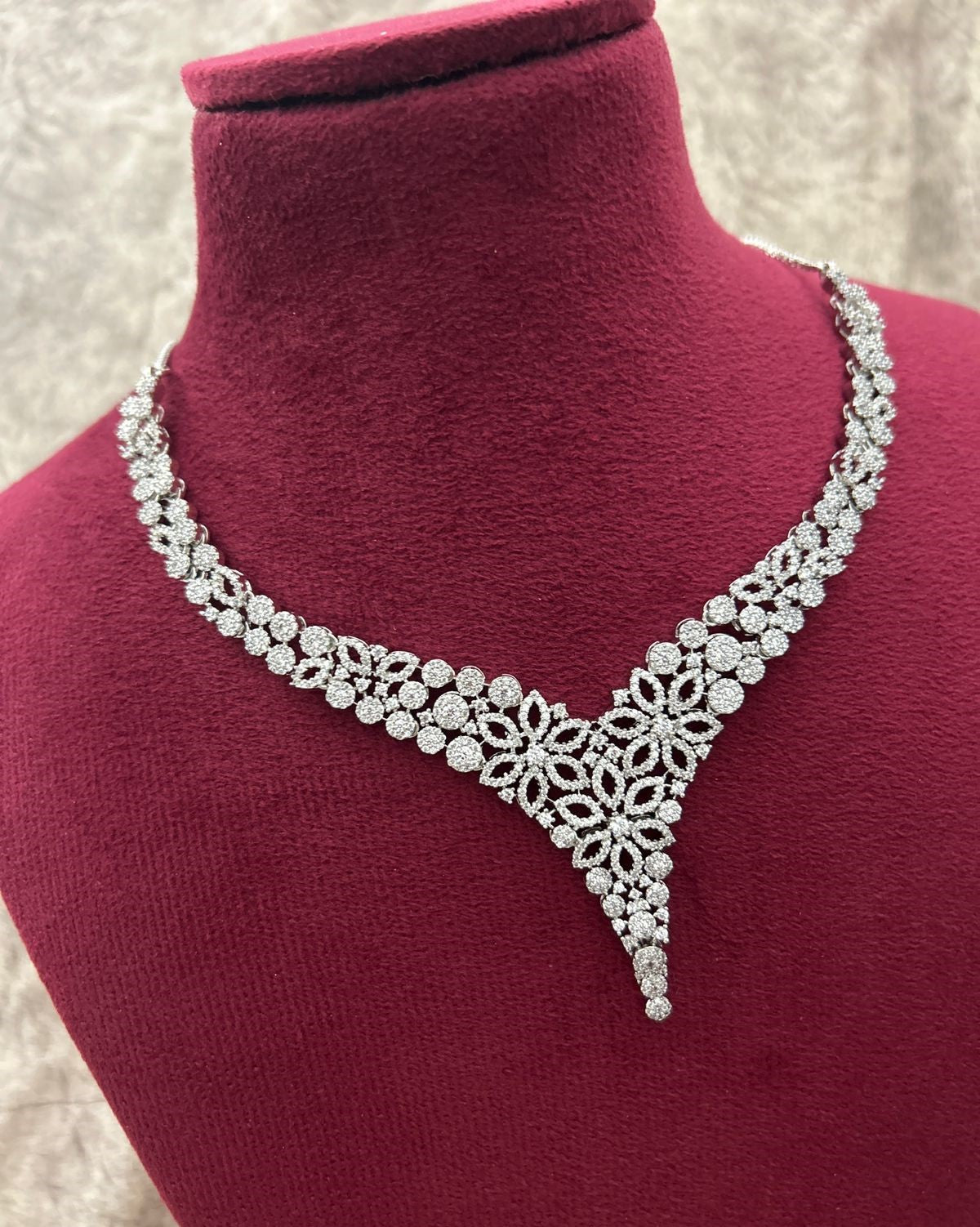 Silver necklace on a mannequin bust with a pink background