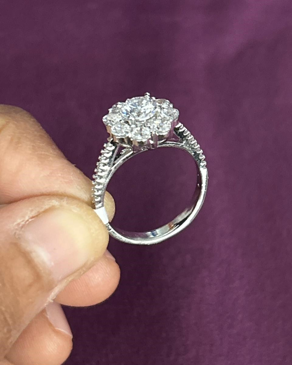 Silver ring with a large diamond held by a hand against a purple background