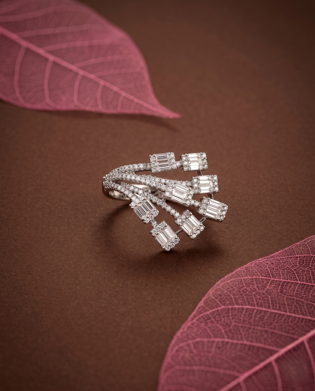 Silver ring with diamond accents on a brown background with pink leaves