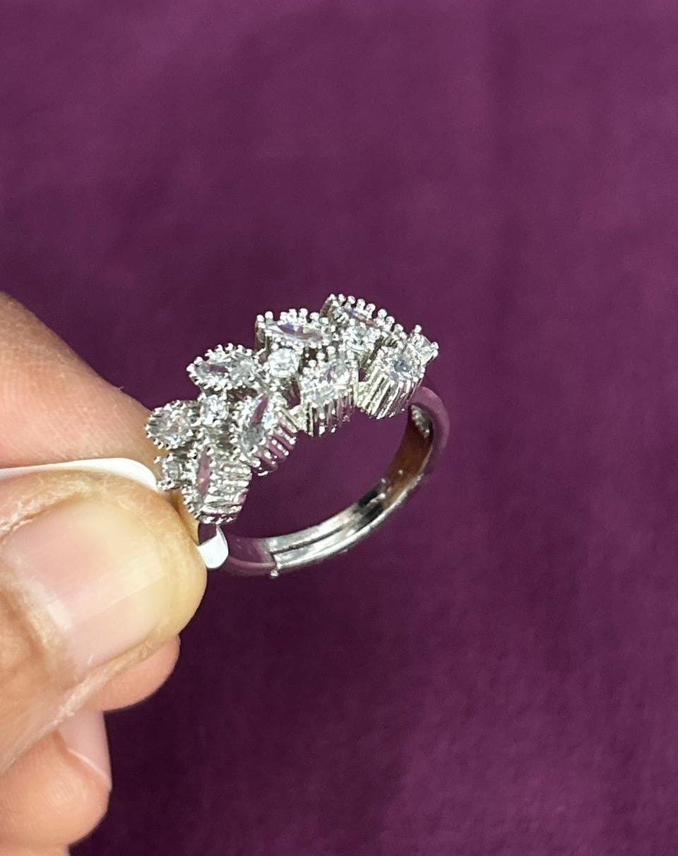 Silver ring with diamonds held by a hand against a purple background