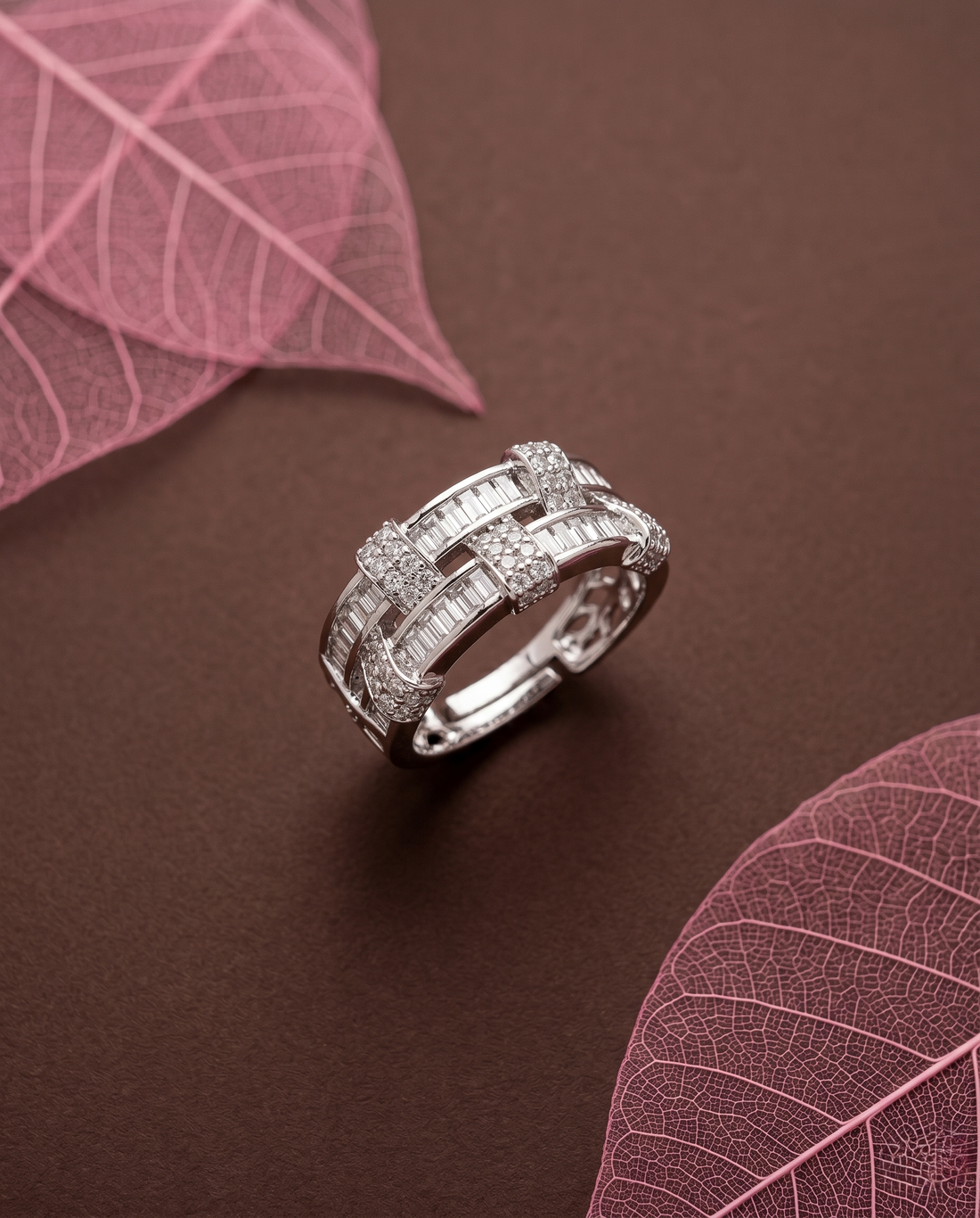 Silver ring with diamonds on a brown surface with pink leaves