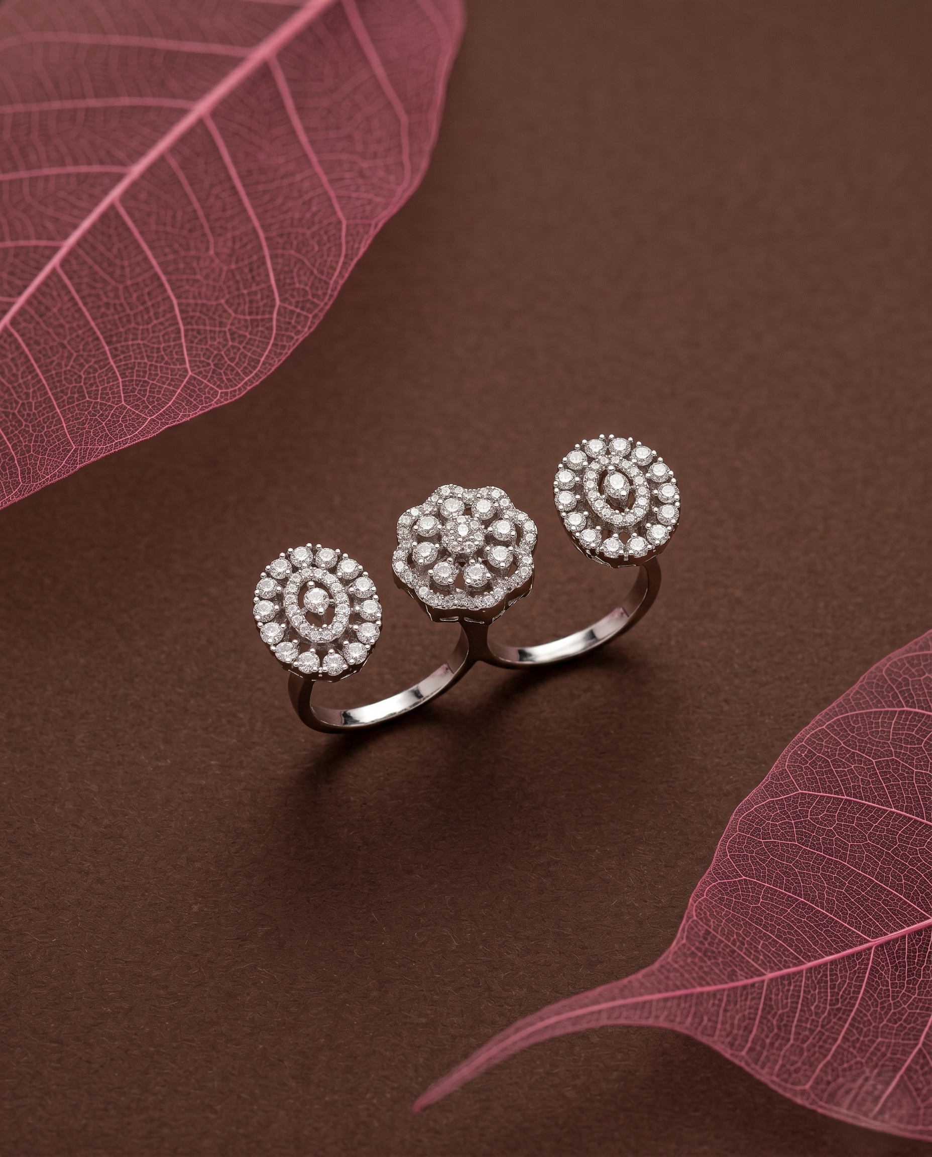 Silver ring with floral design on a brown surface with pink leaves