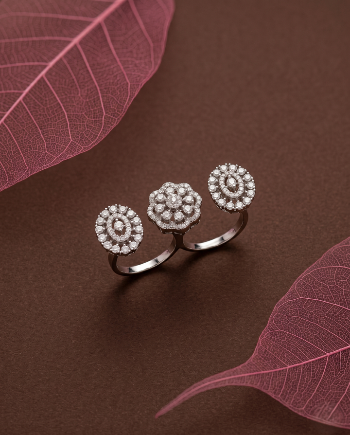 Silver ring with floral design on a brown surface with pink leaves