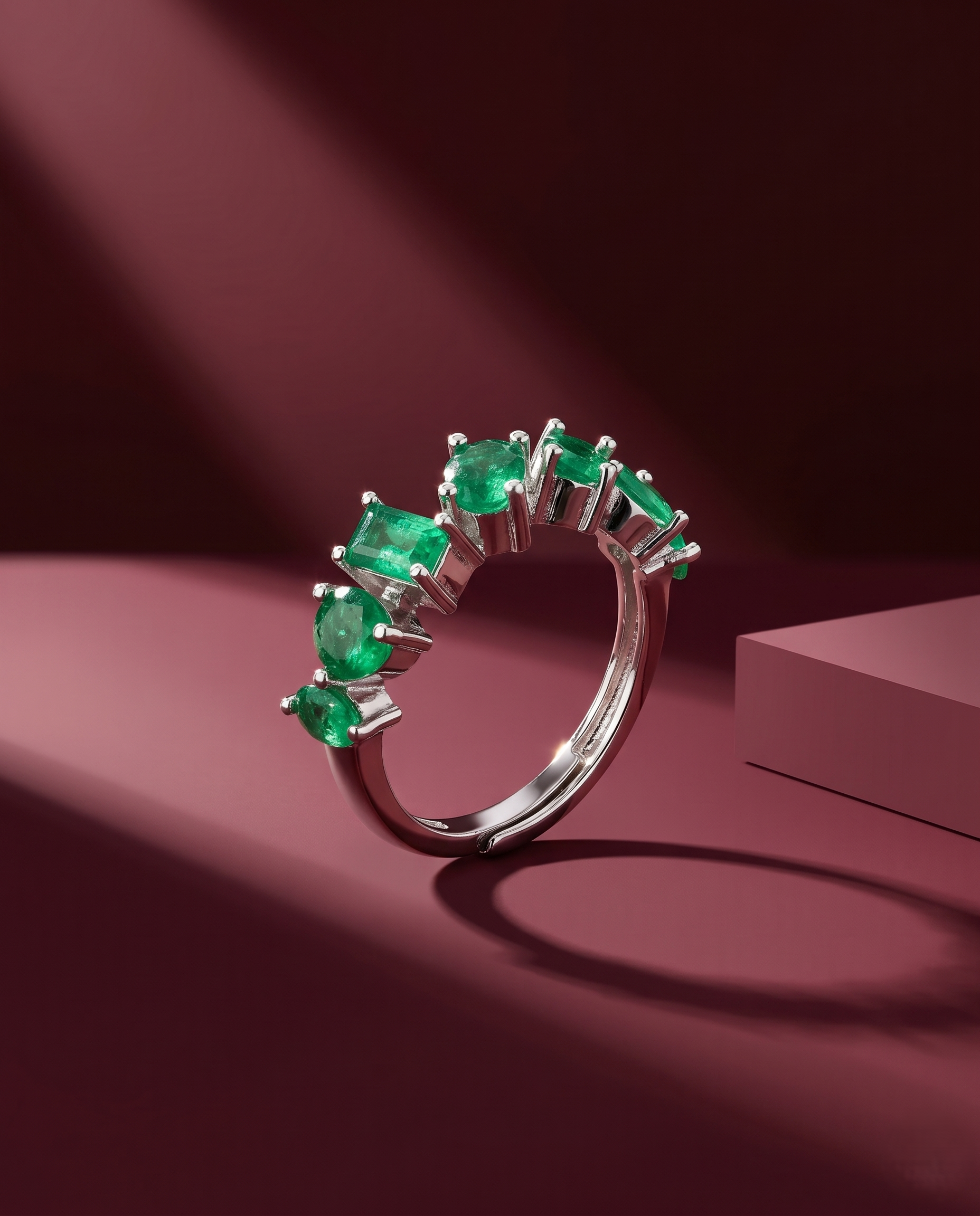 Silver ring with green gemstones on a maroon background