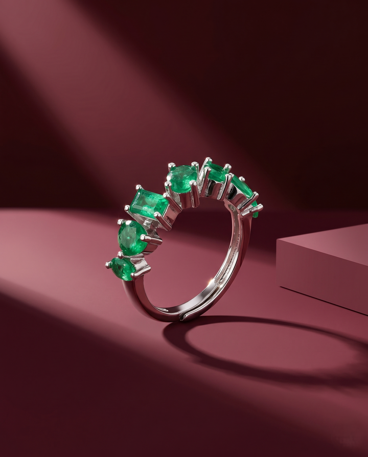 Silver ring with green gemstones on a maroon background