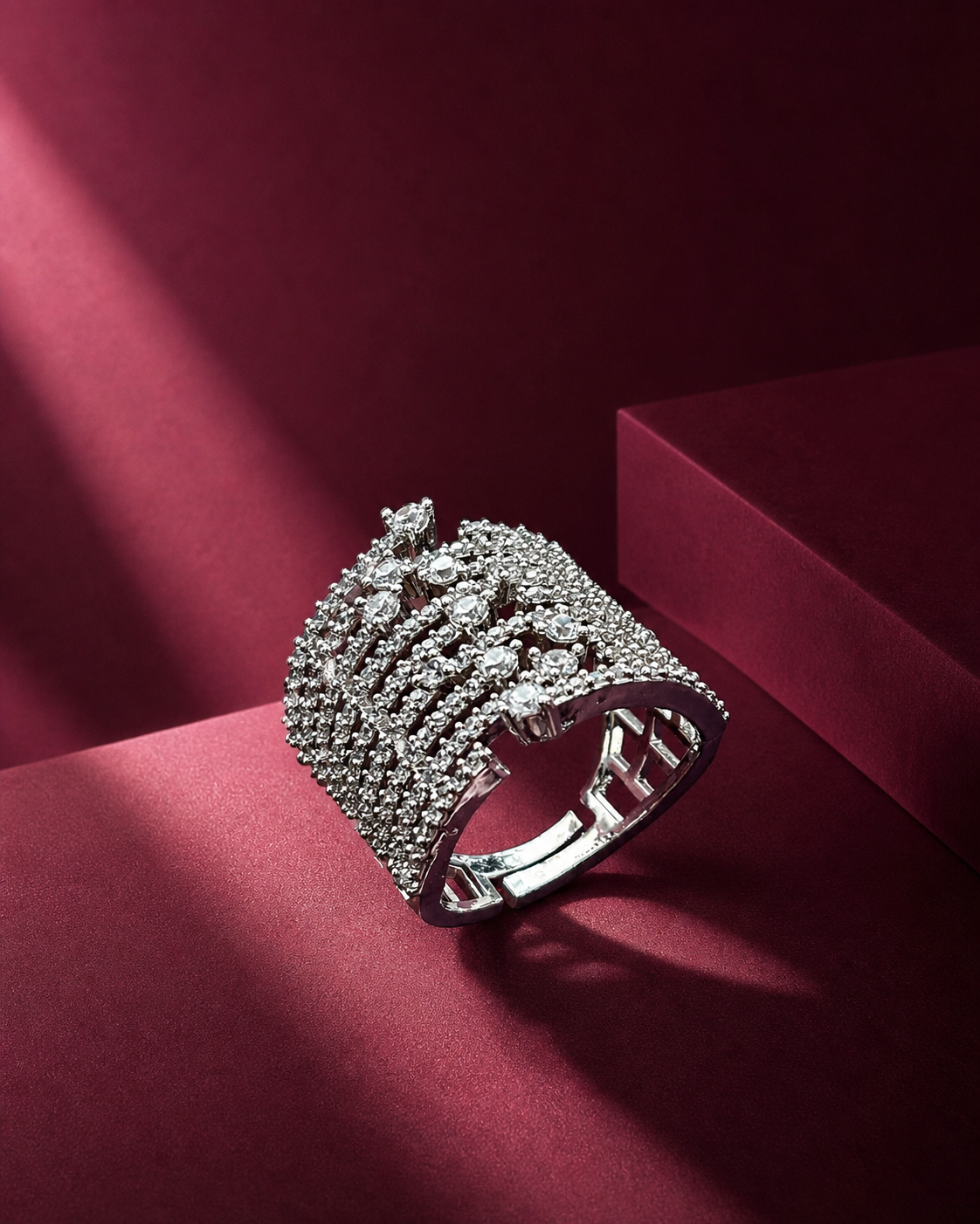 Silver ring with intricate design on a red surface