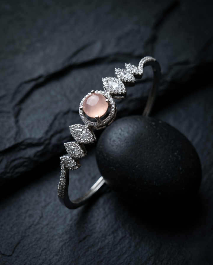 Silver ring with pink gemstone and diamond accents on a dark surface