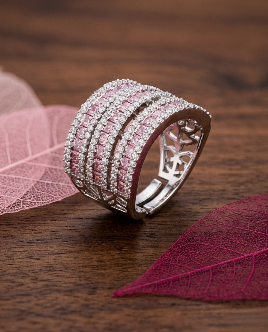 Silver ring with pink gemstones on a wooden surface with pink leaves