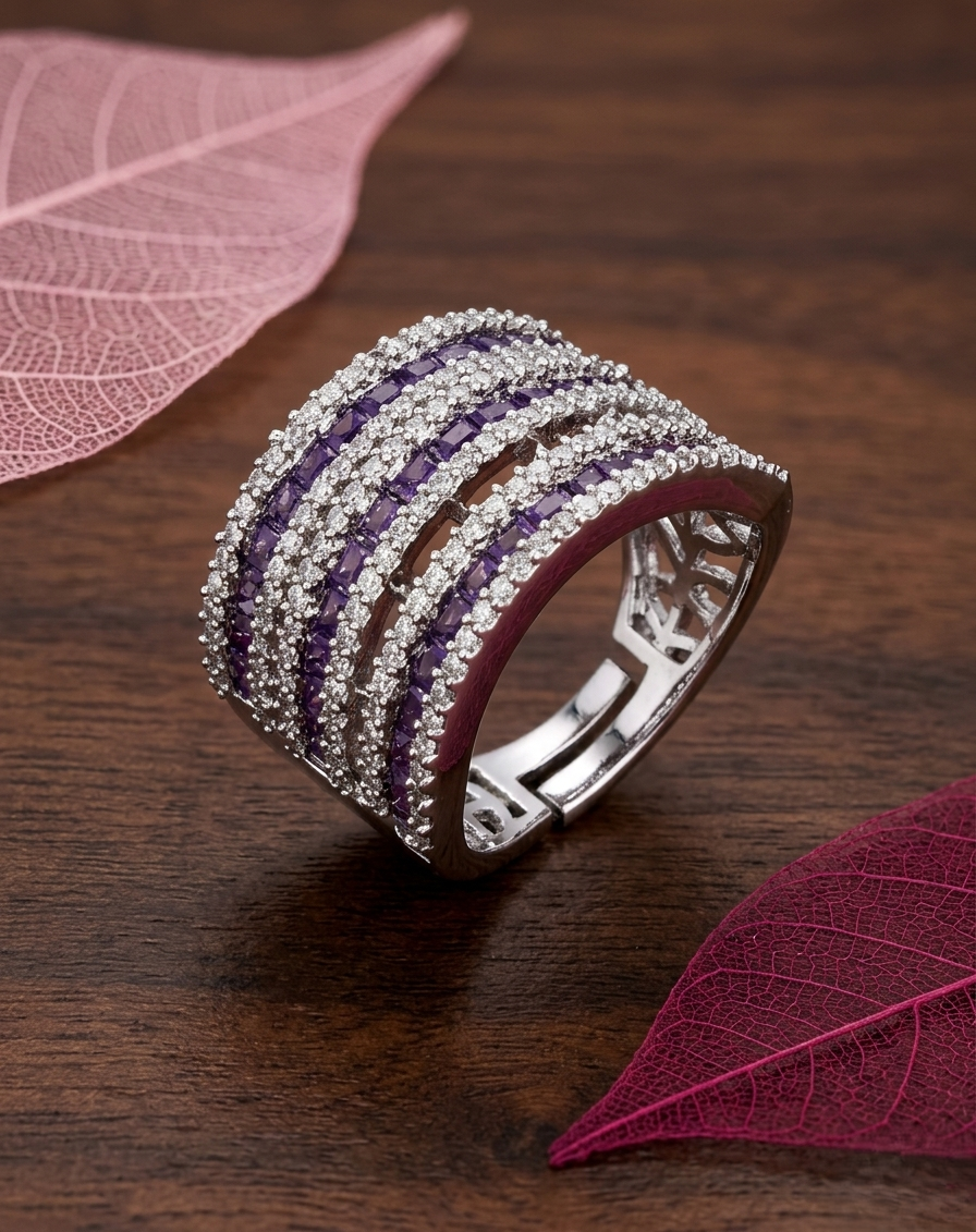 Silver ring with purple stones held by a hand against a dark background