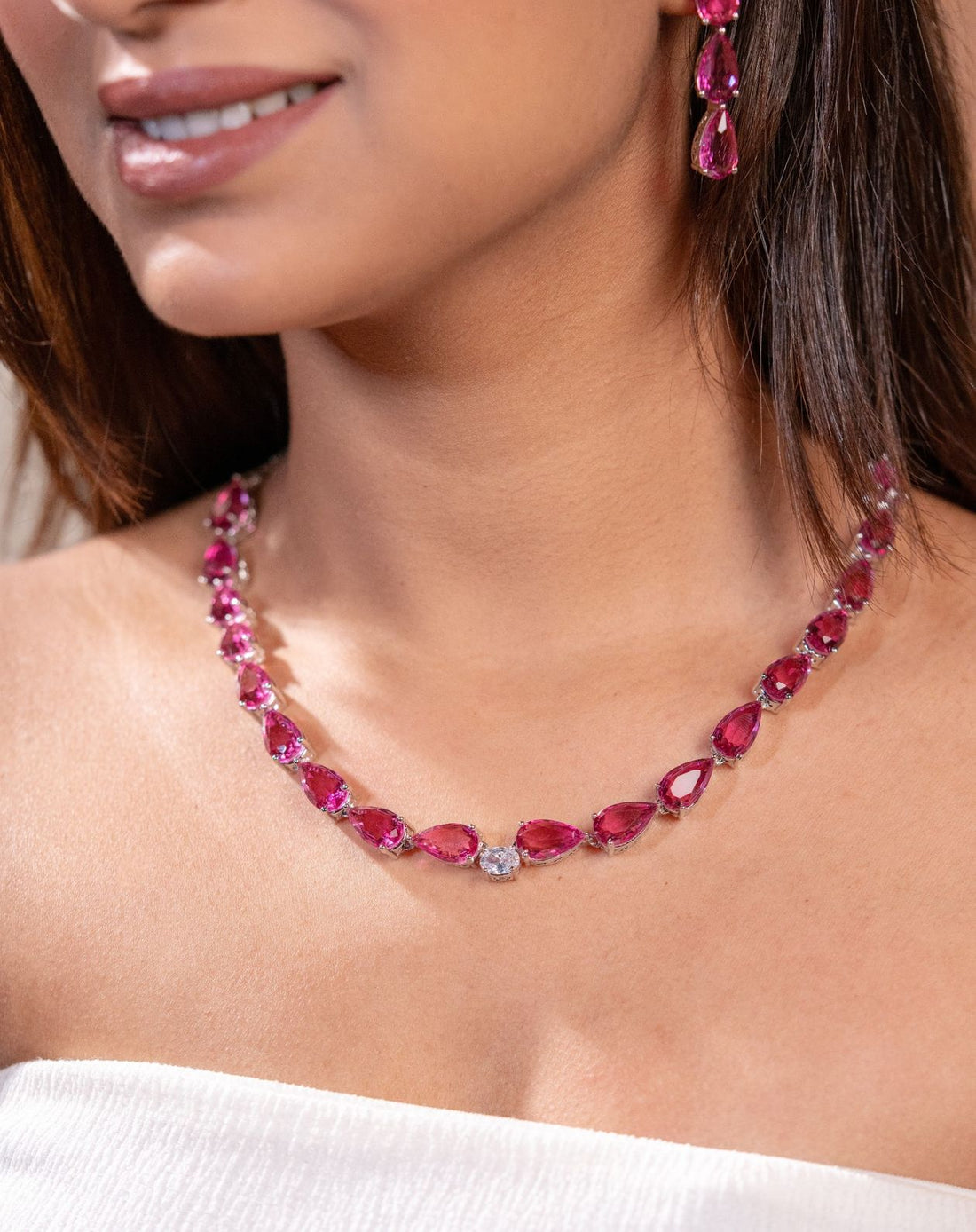 Close-up of a woman wearing a red gemstone necklace and earrings.
