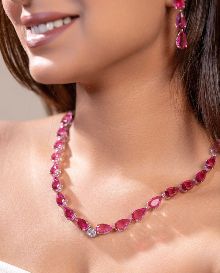 Woman wearing a pink gemstone necklace and earrings.