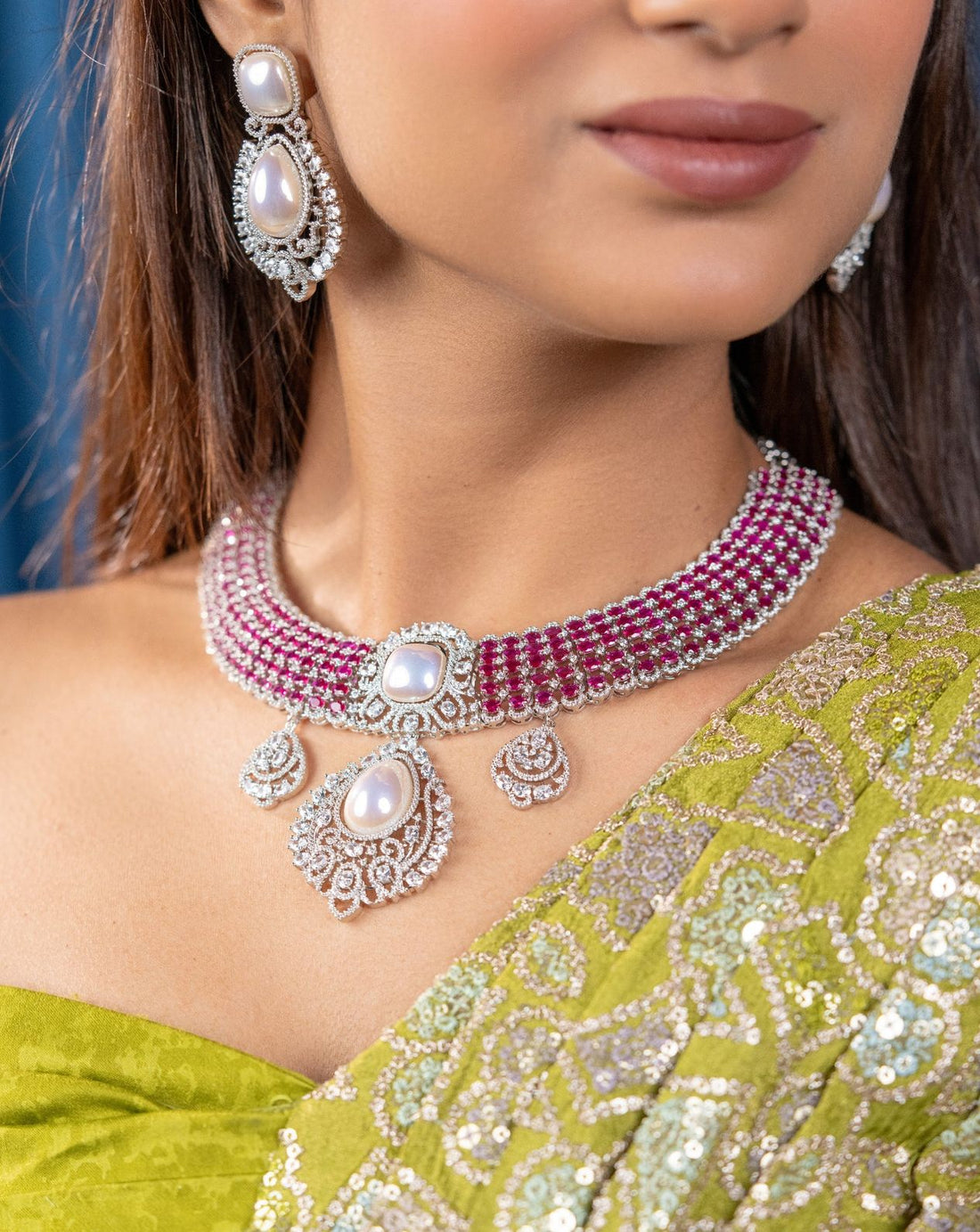 Close-up of a person wearing a green saree with silver and pink jewelry set.