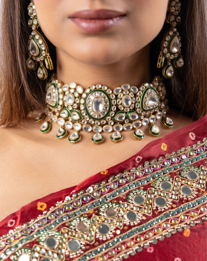 Close-up of a woman wearing an ornate necklace and earrings with a red saree.