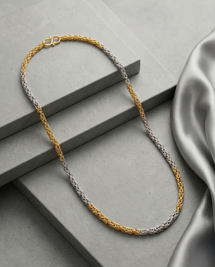 Two-toned gold and silver necklace on a gray surface with a soft fabric background