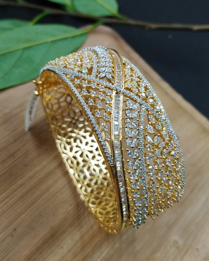 Gold bracelet with intricate design on a wooden surface