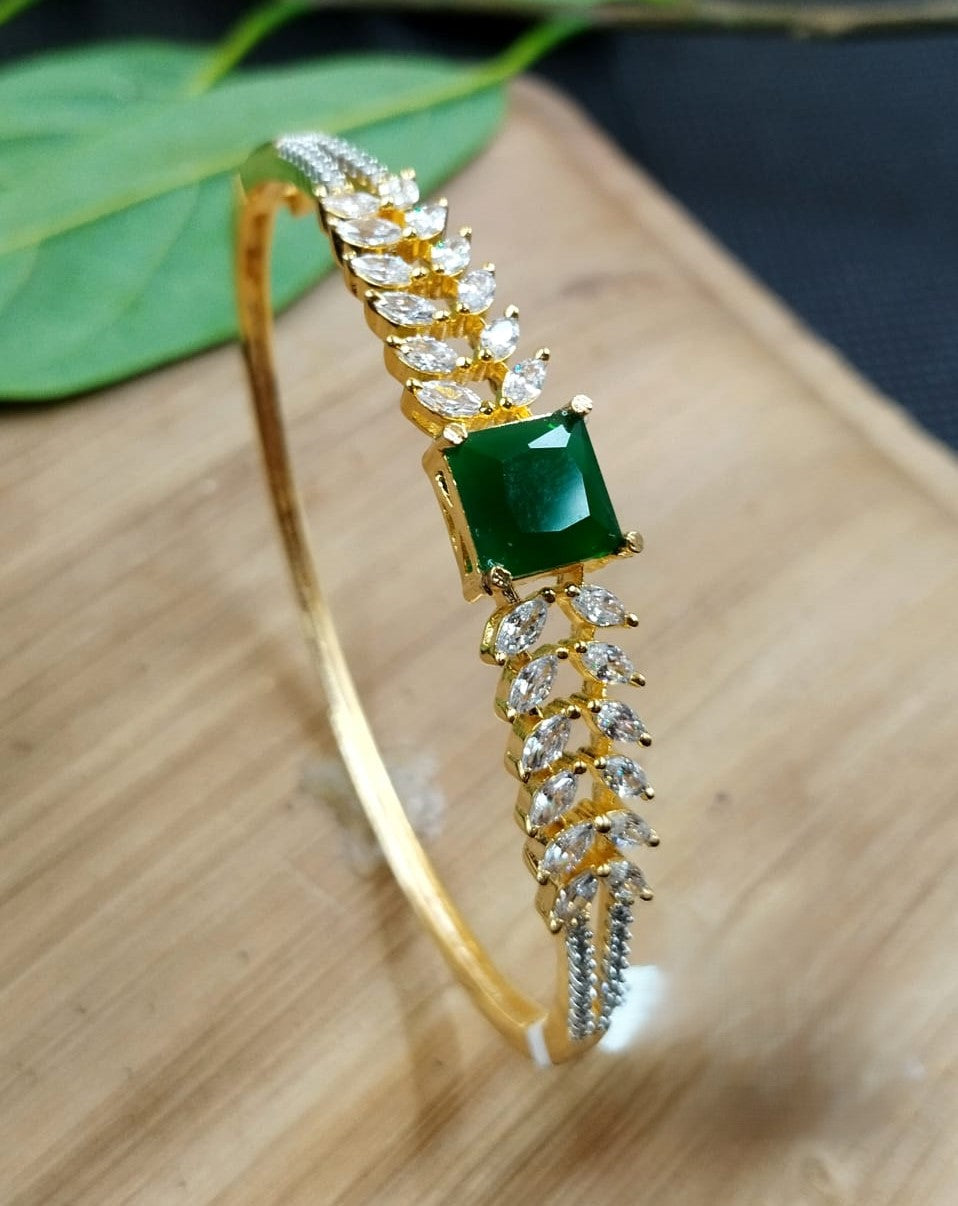 Gold bracelet with a green gemstone on a wooden surface