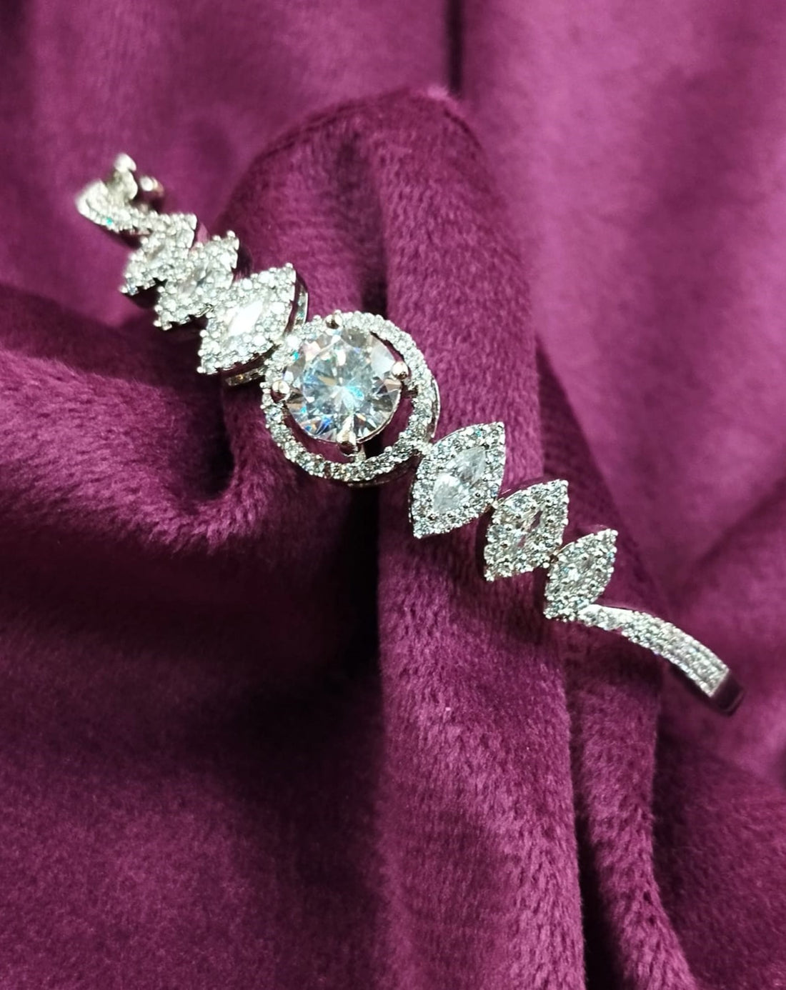 Silver brooch with a central gemstone on a purple fabric background