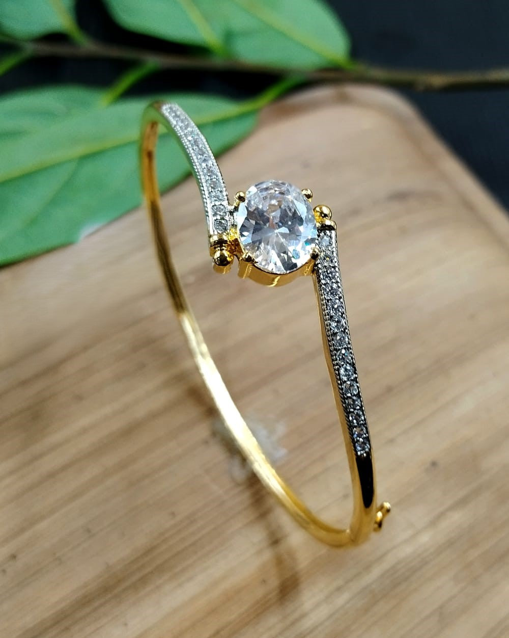 Gold bracelet with a central gemstone on a wooden surface