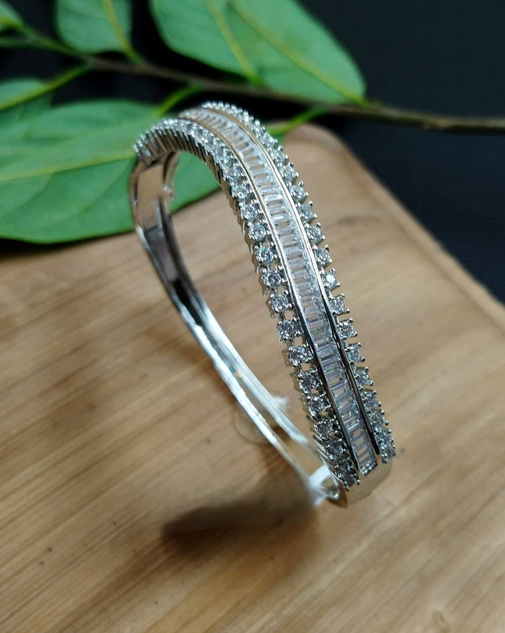 Silver bracelet with gemstones on a wooden surface with leaves in the background