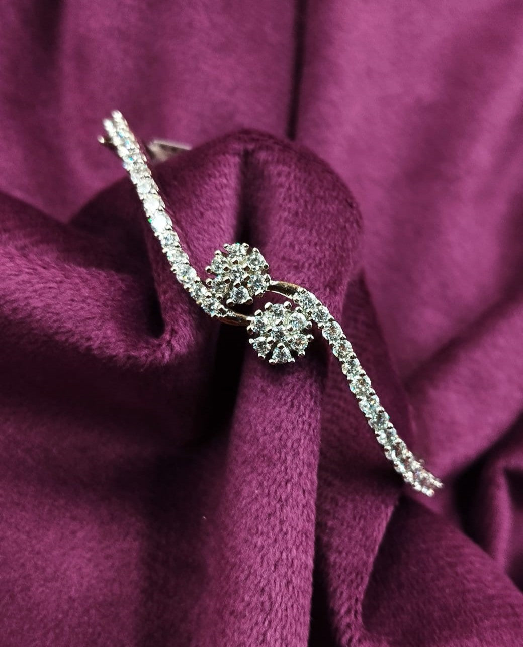 Silver bracelet with a floral design on a purple fabric background