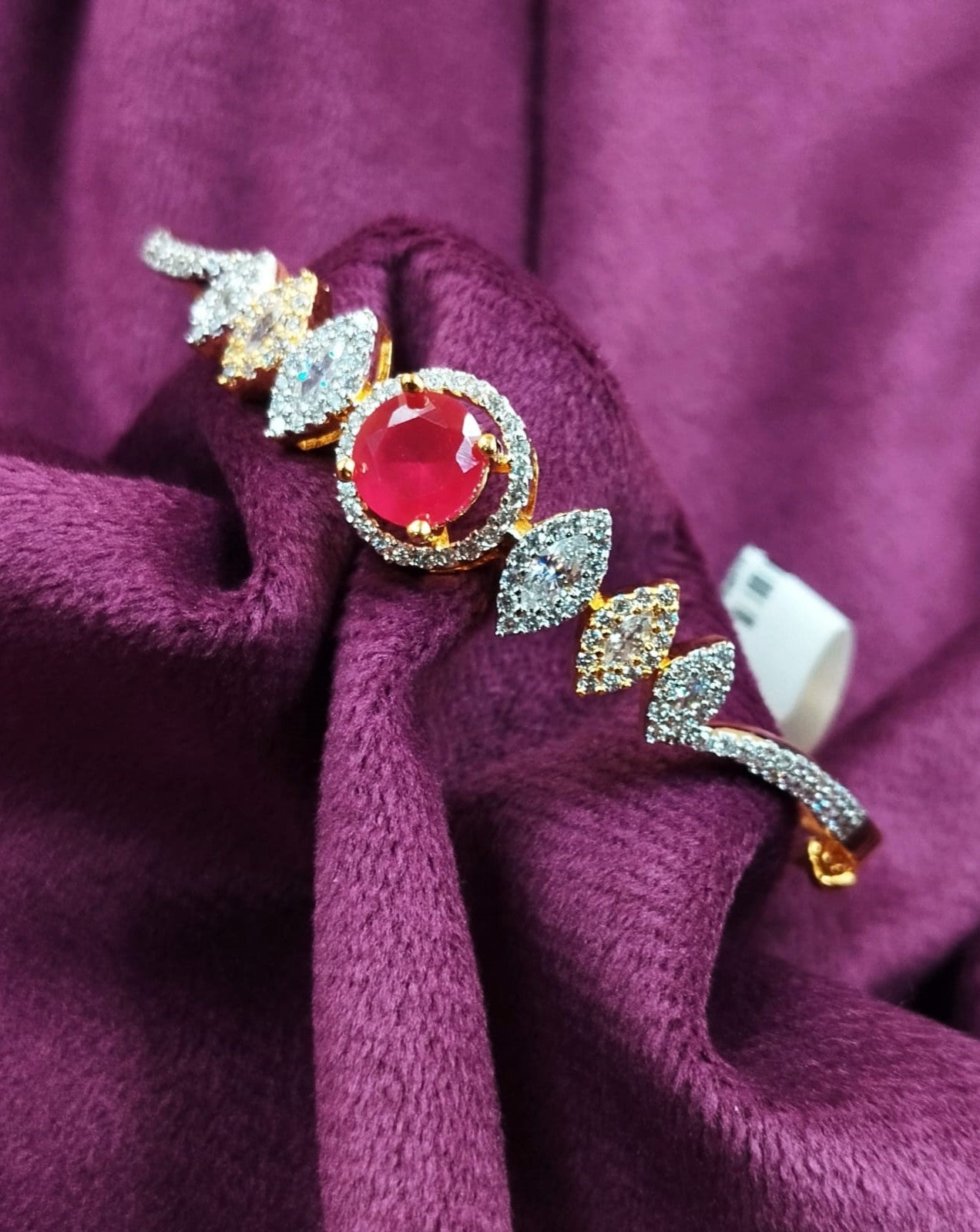 Jewelry with a red gemstone and gold accents on a purple fabric background