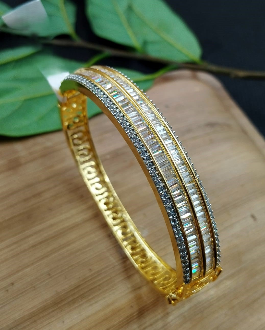 Gold bracelet with embedded stones on a wooden surface