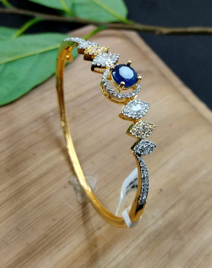 Gold bracelet with blue gemstone and diamonds on a wooden surface