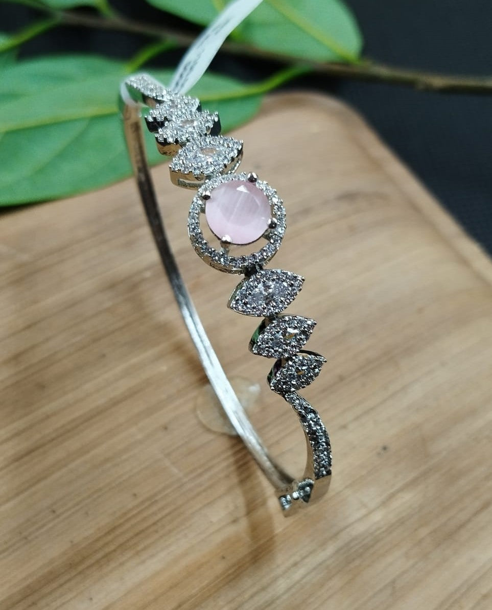 Silver bracelet with pink gemstone on a wooden surface