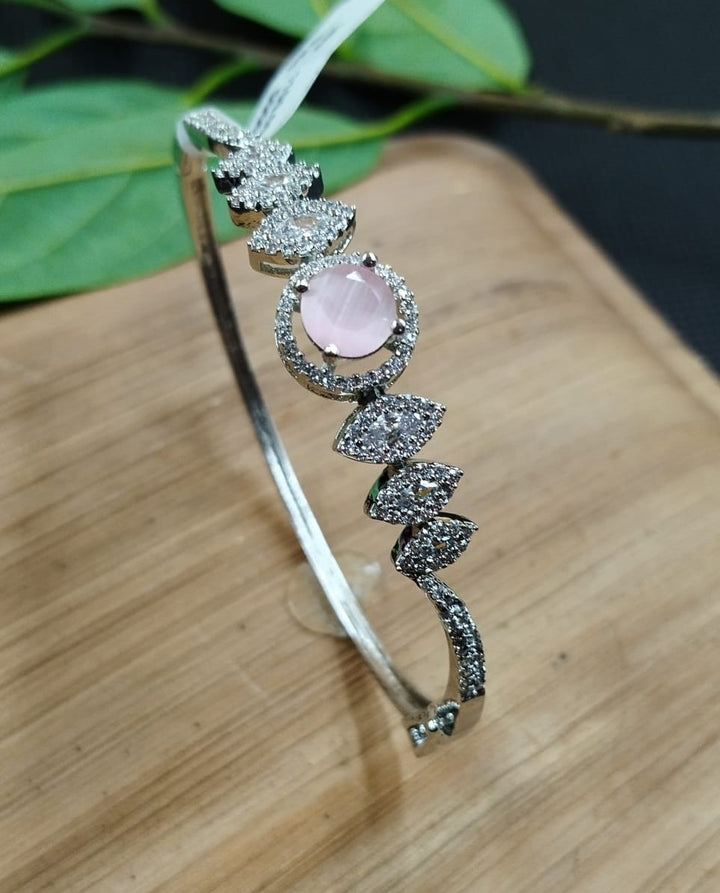 Silver bracelet with pink gemstone on a wooden surface