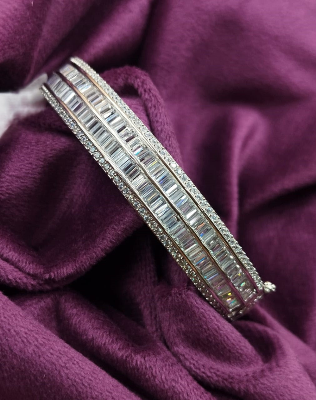 Silver bracelet with gemstones on a purple fabric background