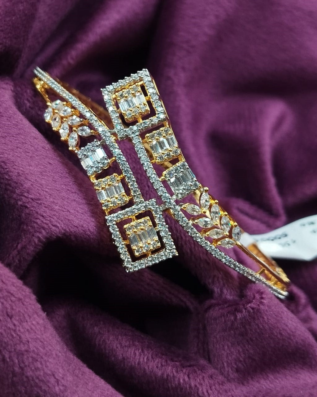 Pair of gold and diamond earrings on a purple fabric background